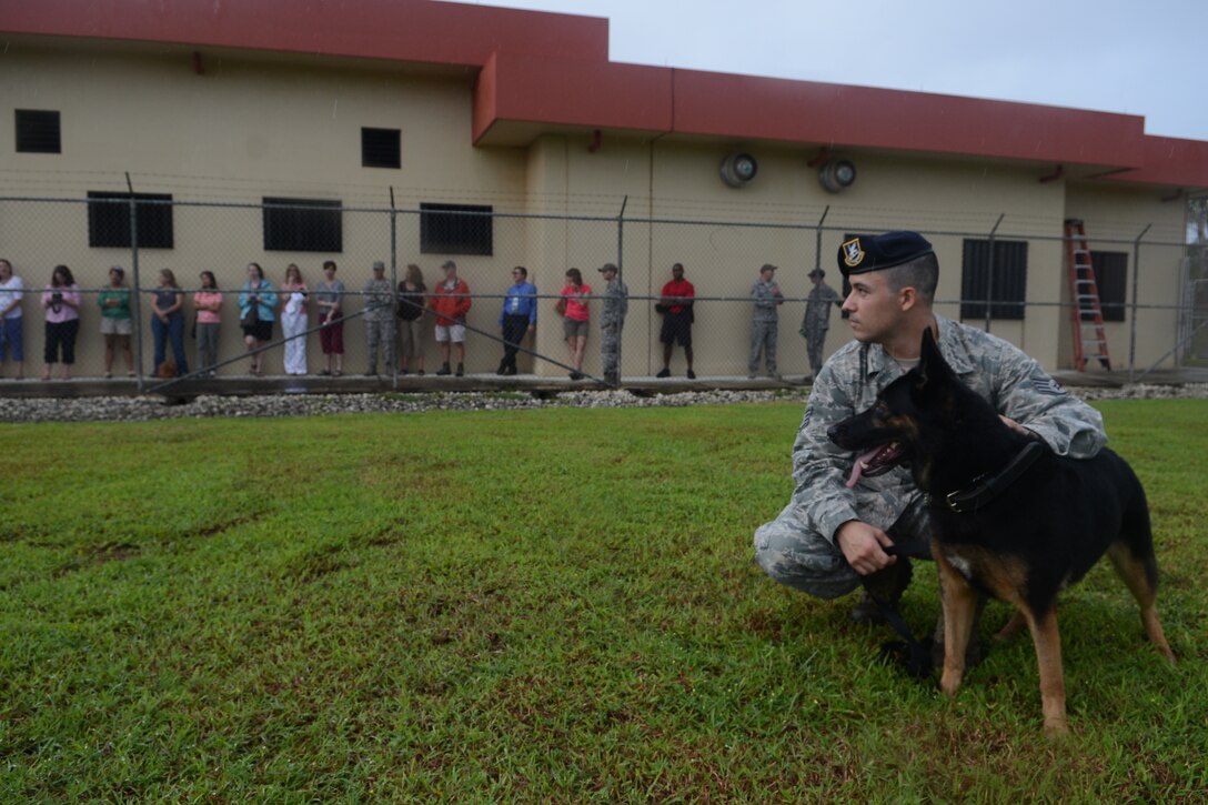 Staff Sgt. Daniel Deleon, 36th Security Forces Squadron military working dog handler, and his dog, “Nouscha,” stand down during a briefing before a dog demonstration for military spouses Oct. 22, 2013 on Northwest Field, Guam. Leadership’s spouses observed the dog team’s capabilities as part of an immersion tour.  (U.S. Air Force photo by Airman 1st Class Emily A. Bradley/Released)