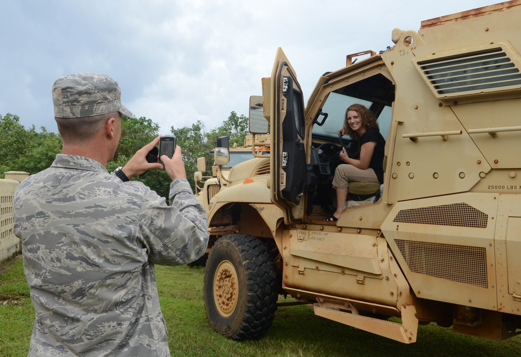 Col. Jason Armagost, 36th Wing vice commander, takes a photo of his wife inside a mine-resistant, ambush-protected vehicle during a tour for military spouses Oct. 22, 2013 on Northwest Field, Guam. The spouses learned about the history of Northwest Field, observed the training site for upcoming Silver Flag exercises, rode in a MRAP egress trainer and watched a military working dog demonstration. (U.S. Air Force photo by Airman 1st Class Emily A. Bradley/Released)