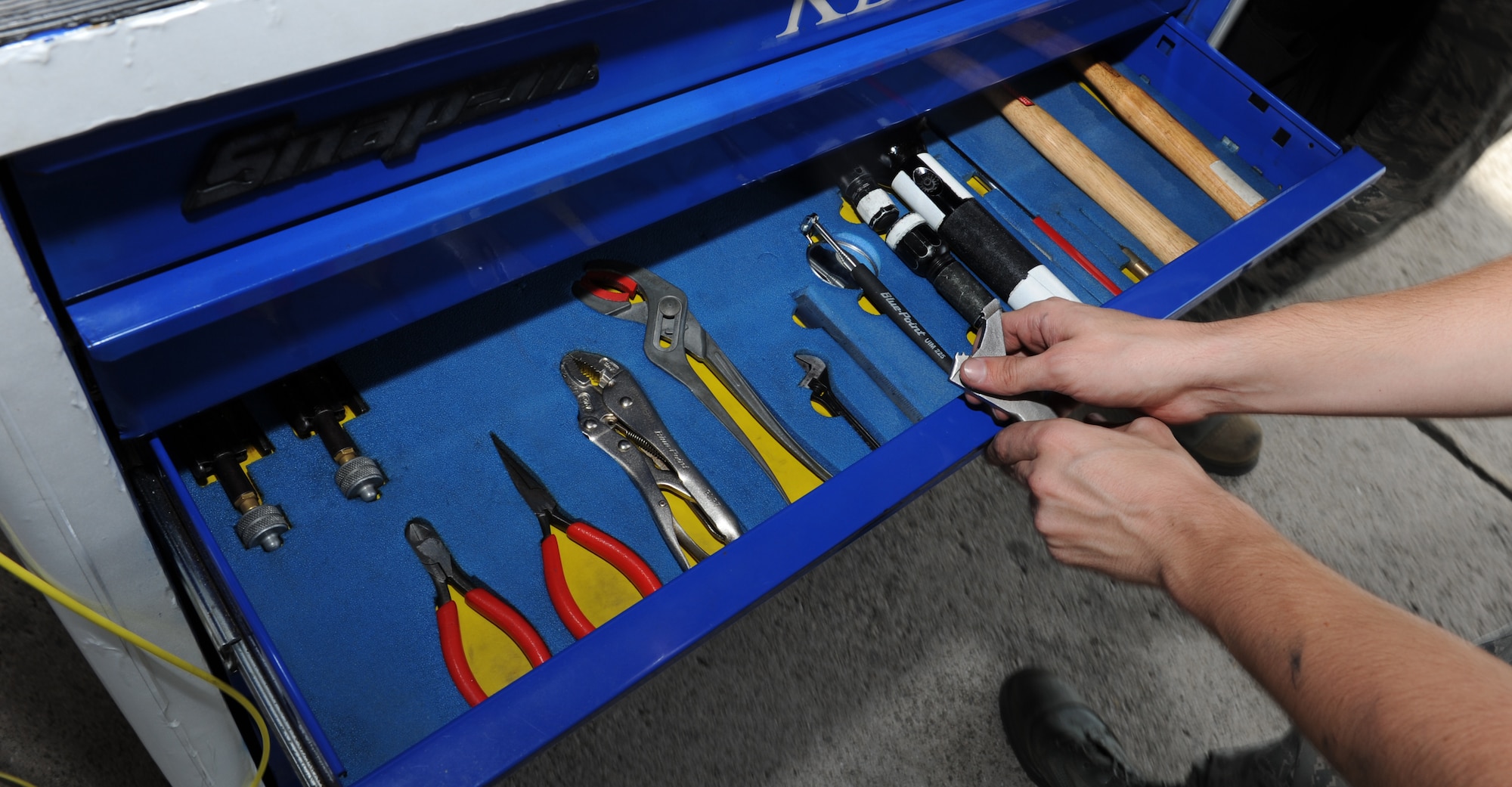 U.S. Air Force Airman 1st Class Daniel Henderson, 44th Aircraft Maintenance Unit weapons load crew member, puts away tools used during a weapons load competition on Kadena Air Base, Japan, Oct.18, 2013. Proper placement and use of the tools were a part of the assessment, that tested the team's ability to successfully load the weapons safely, quickly and in the correct manner. (U.S. Air Force photo by Airman 1st Class Keith James)