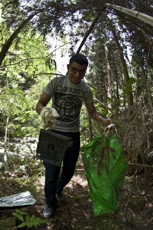 A Single Marine Program cleanup event participant picks up trash while walking through one of the trails at Futashika Umezu Falls and park, May 17, 2013. “I like to volunteer to a cause,”said Maria Molinalemus, SMP river cleanup participant. “If you can’t give out money, then you have to give a piece of yourself and I think helping out the community is the best thing. ... It’s about helping out.”