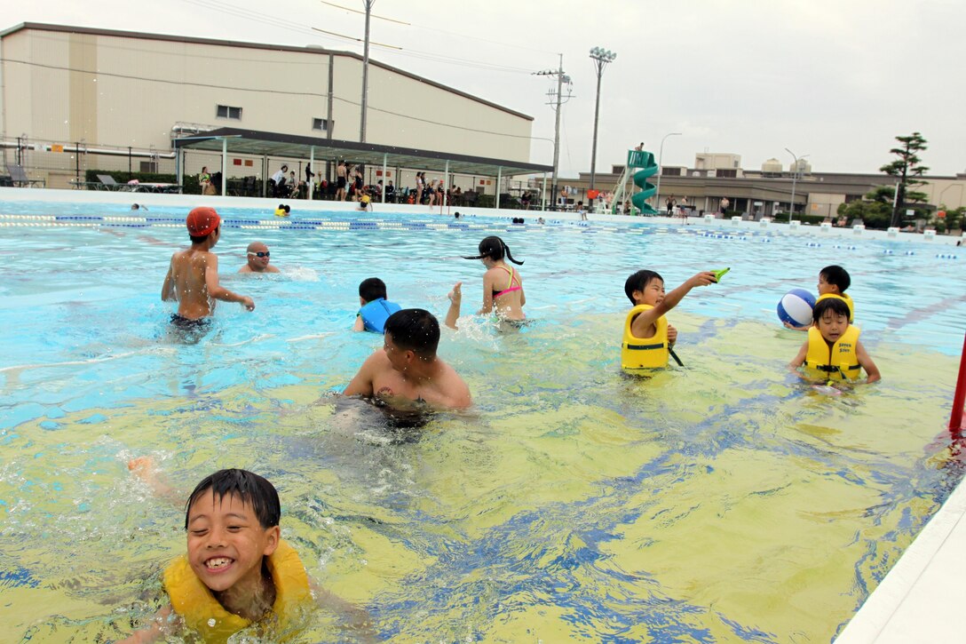 Children from the Yahata Gakuen Children’s Home swim with Marines and sailors from Marine Wing Support Squadron 171 during a community relations event at the WaterWorks outdoor pool, June 30, 2013. The children whirled and splashed about in the pool with servicemembers to cool off from the activities that were played in the hot, humid weather earlier in the day.