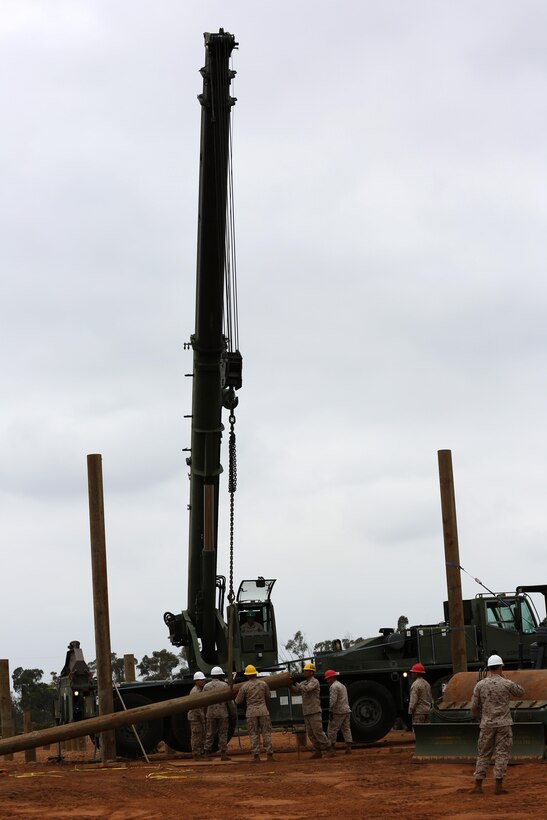 Combat engineers with Marine Wing Support Squadron 373 help a heavy equipment operator guide a pole into the ground at the obstacle course construction site aboard Marine Corps Air Station Miramar, Calif., Oct. 24. Combat engineers have a wide variety of skills; construction and site management are just two skills they constantly work to master.