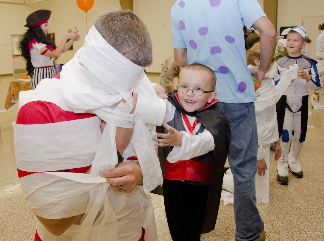 Cub Scout Nathaniel Liming wraps his den leader, Shaun Donahue, in toilet paper for the "Mummy Wrap" game during Cub Scout Pack 225's Spookeree, in classroom 7 of building 5082, Oct. 19, 2013. Pack 225 held a Spookeree, in which they received the belt loops and merit badges they recently earned, participated in a costume contest, mini parade and assorted activities. (U.S. Marine Corps photo by Kristen Wong)