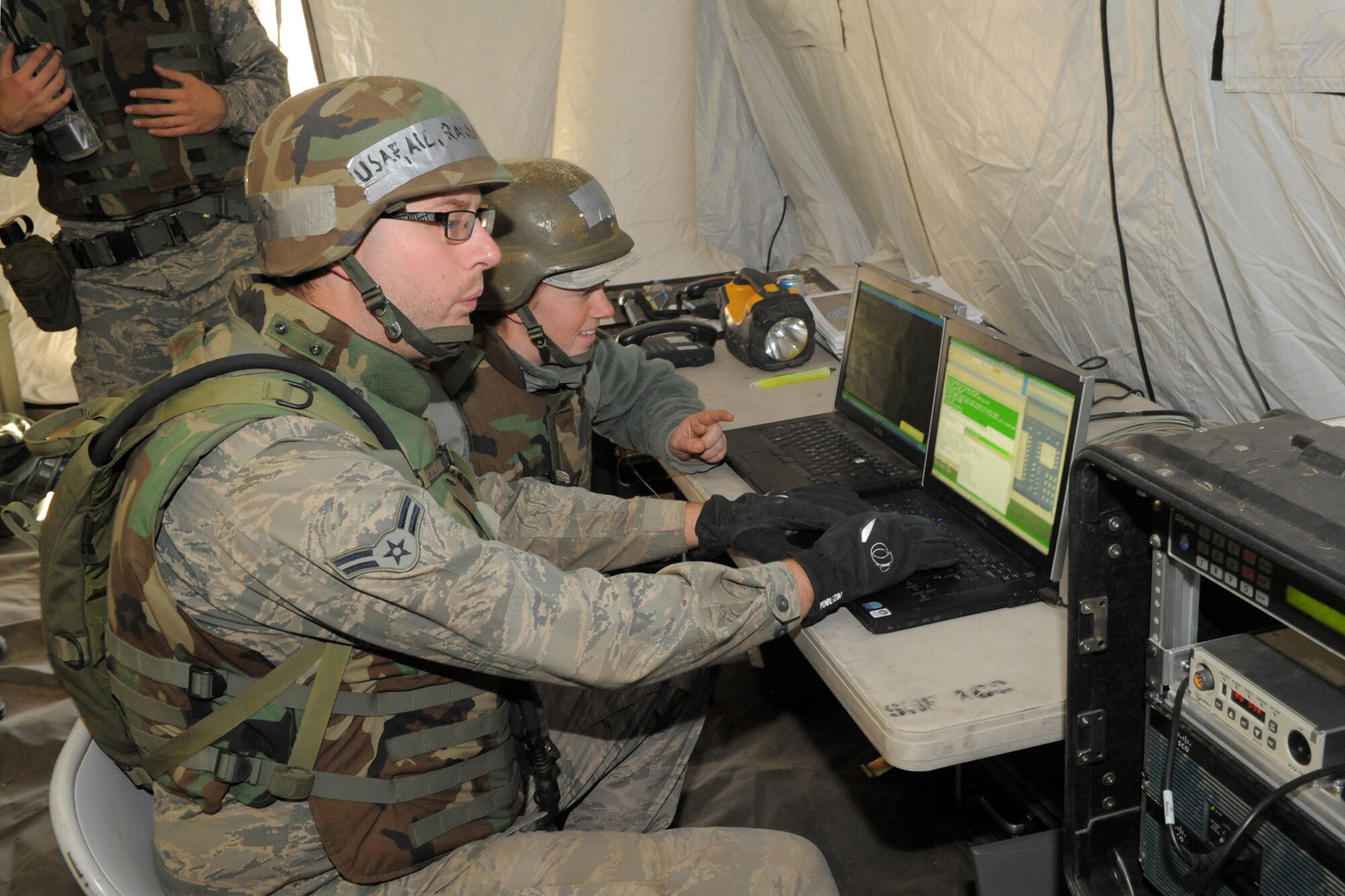 Airman 1st Class Randall Seymour and Senior Airman Kari Barber, Theatre Deployable Communications, run computer simulations during a 729th Air Control Squadron field training exercise Oct. 24, 2013, at Hill Air Force Base, Utah. (U.S. Air Force photo by Todd Cromar/Released)

