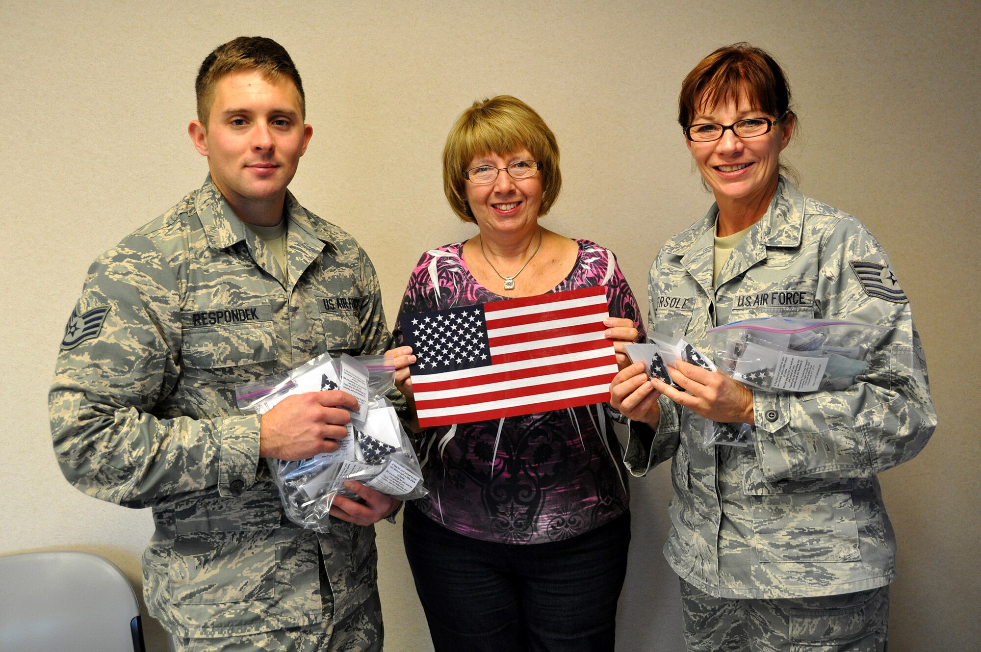 Nancy Despard of the American Legion Ladies Auxiliary Post 567, Orchard Park N.Y. presents 230 eight inch by 12 inch folded American flags to Staff Sgt. Nicholas Respondek, 914th Airlift Wing, and Tech. Sgt. Laura Eversole, 914th Force Support Squadron, October 23, 2013 at the Niagara Falls Air Reserve Station, N.Y.  These flags will be distributed by the Airmen while deployed overseas.  (U.S. Air Force photo by Master Sgt. Kevin Nichols)