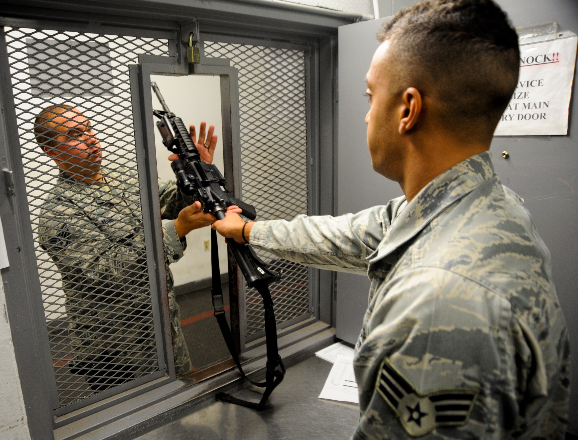 U.S. Air Force Staff Sgt. Zachary Regan, 355th Security Forces Squadron security forces NCO in charge of armory, returns an M-4 Carbine to Senior Airman James Vossah, 355th Security Forces Squadron armory attendant, at Davis-Monthan Air Force Base, Ariz., Oct. 23, 2013. At the end of their shifts security forces’ members must return all weapons and equipment to the armory for accountability and safety. (U.S. Air Force photo by Senior Airman Sivan Veazie/Released)