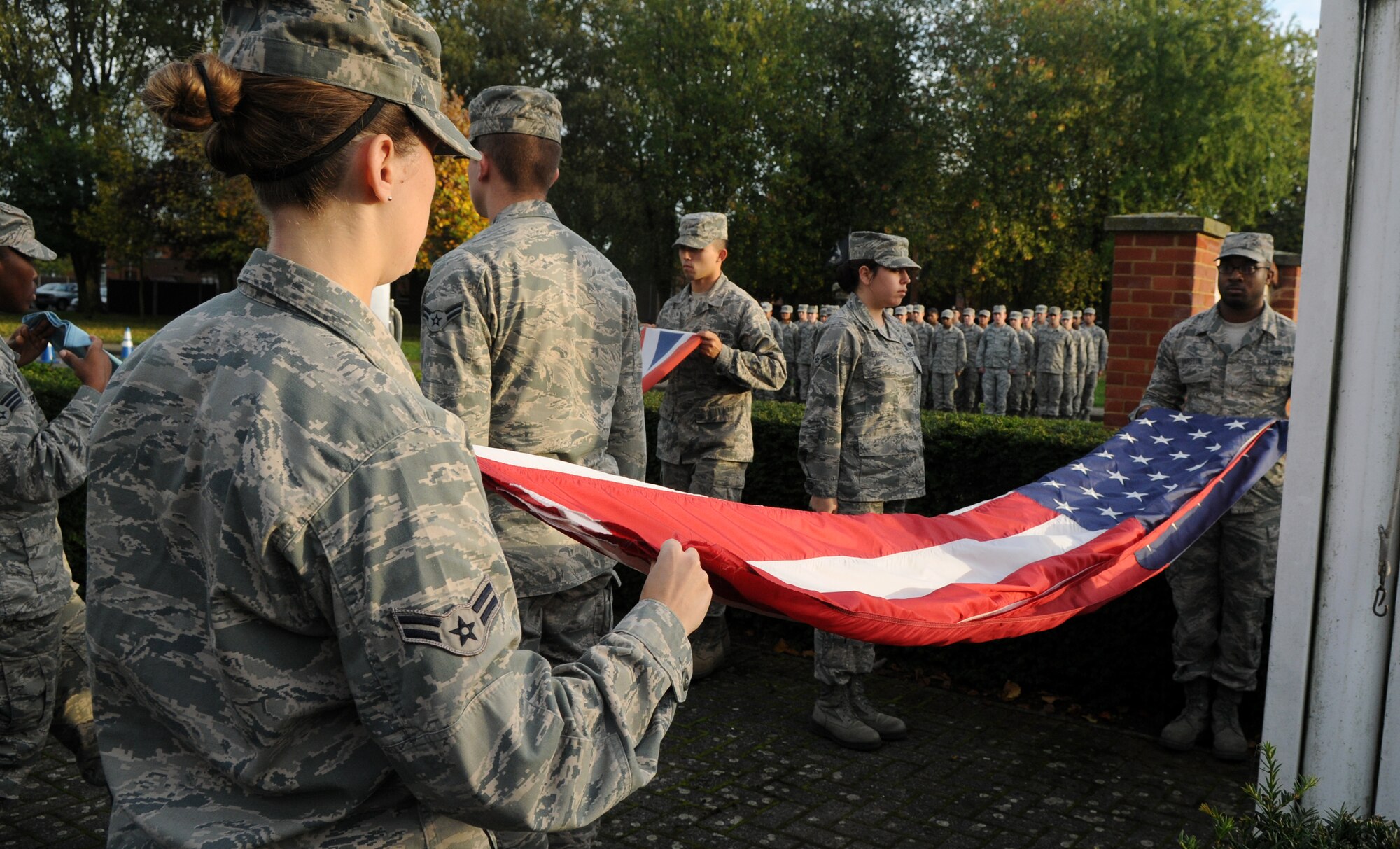 Members of the Team Mildenhall Honor Guard and Airmen Committed to Excellence fold the U.S. flag and Royal Air Force ensign during a retreat ceremony Oct. 25, 2013, on RAF Mildenhall, England.  A retreat ceremony, in which the U.S. flag and Royal Air Force ensign are retired, takes place on the last Friday of every month. A team of Airmen secured both the U.S. flag and the RAF ensign as part of the ceremony, which honors the colors and signals the official end of the duty day. (U.S. Air Force photo by Tech. Sgt. Austin May/Released)