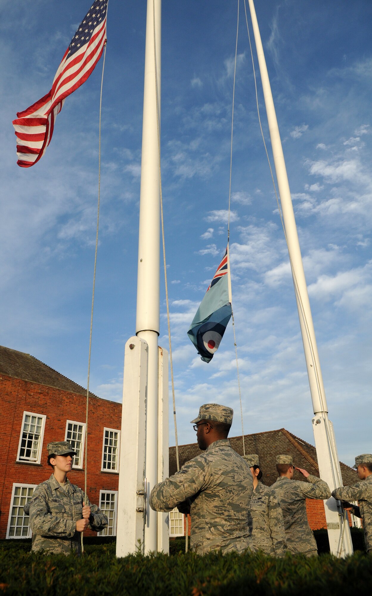 Members of the Team Mildenhall Honor Guard and Airmen Committed to Excellence lower the U.S. flag and Royal Air Force ensign during a retreat ceremony Oct. 25, 2013, on RAF Mildenhall, England. Retreat is a long-standing tradition honoring the flag and signaling the end of the duty day. A retreat ceremony, in which the U.S. flag and Royal Air Force ensign are retired, takes place on the last Friday of every month. (U.S. Air Force photo by Tech. Sgt. Austin May/Released)