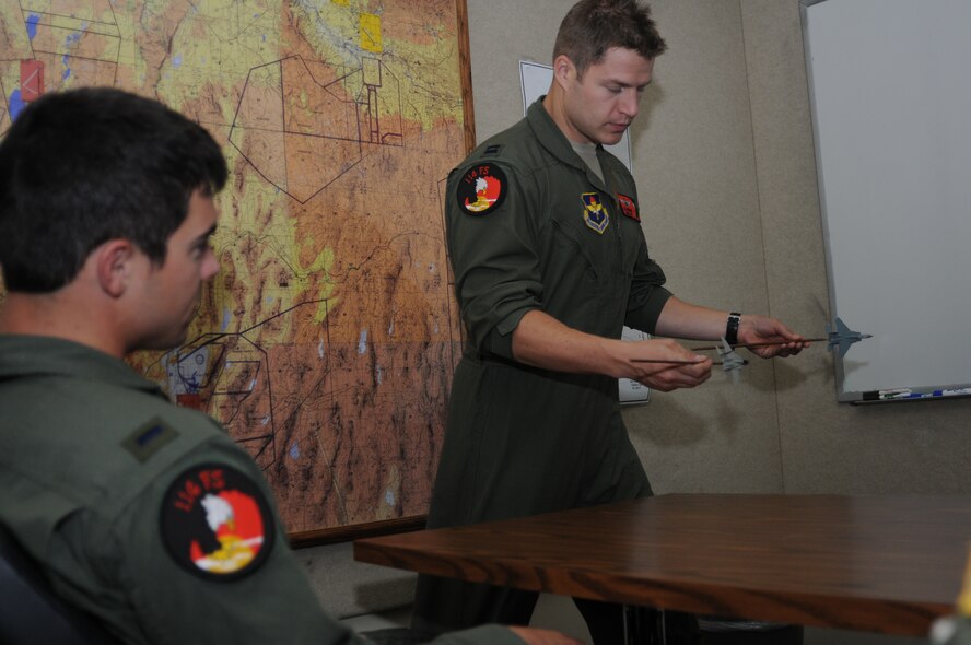 U.S. Air Force Capt. Adam Gaudinski, 173rd Fighter Wing F-15 instructor pilot, explains various maneuvering positions to 1st Lieutenant Matt Scott, a F-15 student pilot, at Kingsley Field, Klamath Falls, Ore. The 173rd Fighter Wing is home to the sole F-15C training school house for the United States Air Force.  (U.S. National Guard photo by Master Sgt. Jennifer Shirar/released)