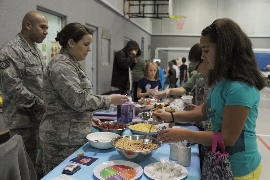 1st Lt. Maggie Mason, 341st Medical Operations Squadron Health and Wellness Center member, hands out fruit to children during the Health and Safety Fair at the Youth Center on Oct. 17. Representatives from the HAWC and the 341st MDOS also hosted a dental health, fitness scholastics and sugar shocker booth.  (U.S. Air Force photo/Senior Airman Katrina Heikkinen)
