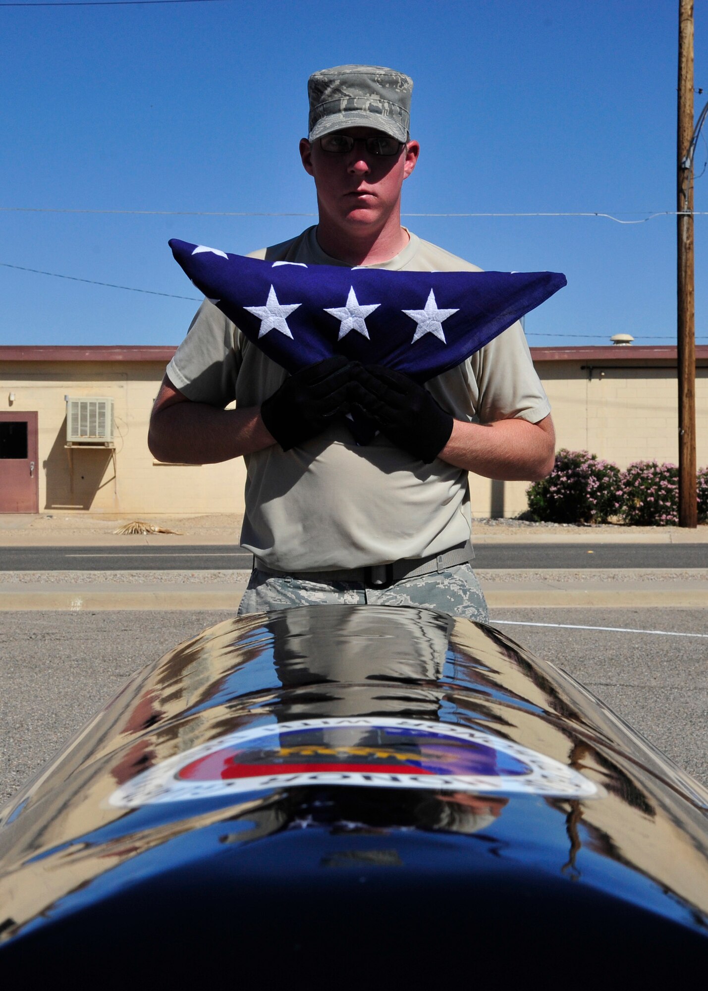 Senior Airman Ethan Retallack, 56th FSS honor guardsman, holds the flag in front of a mock casket after doing a full dress on the flag. Full honors are performed for retired vets, which includes executing a six-man casket sequence. (U.S. Air Force photo/Senior Airman Grace Lee)