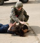 Senior Airman Sorrell Hatrick, 8th Civil Engineer Squadron, restrains Airman 1st Class Kolina Burton, 8th Security Forces Squadron scenario opposition force member, during a training exercise at Kunsan Air Base, Republic of Korea, Oct. 24, 2013.  Airmen from the 8th CES trained with the 8th SFS on how to defend their compound. The 8th SFS trained the Red Devils on communication tactics, apprehending suspects and manning defensive positions. (U.S. Air Force photo by Senior Airman Armando A. Schwier-Morales/Released)