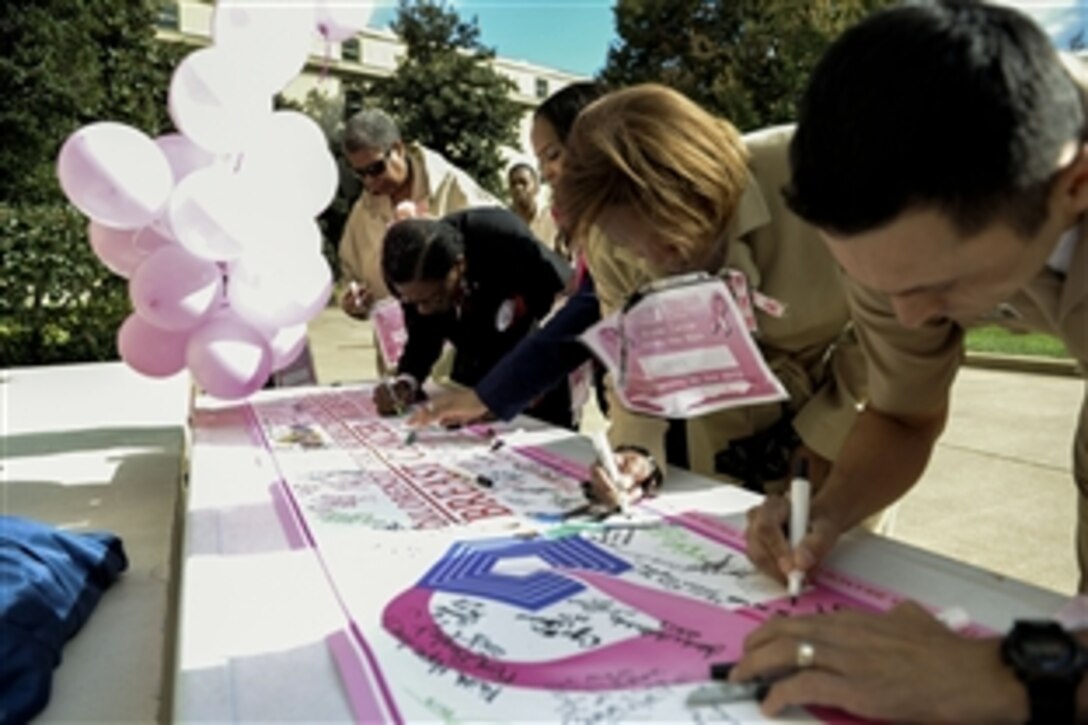 Defense Department civilians and service members and breast cancer survivors sign a banner during the Breast Cancer Awareness Walk in the Pentagon's center courtyard, Washington, D.C., Oct. 24, 2013. The walk was sponsored by the Pentagon’s DiLorenzo Tricare Health Clinic.