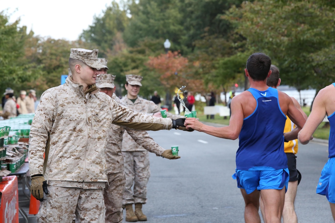 A runner takes a cup of Gatorade from a Marine during the Marine Corps Marathon in Washington, D.C., on Oct. 27, 2013. More than three dozen Marines and civilian volunteers handed out water and Gatorade at Water Point 6 which was 13 miles into the race.