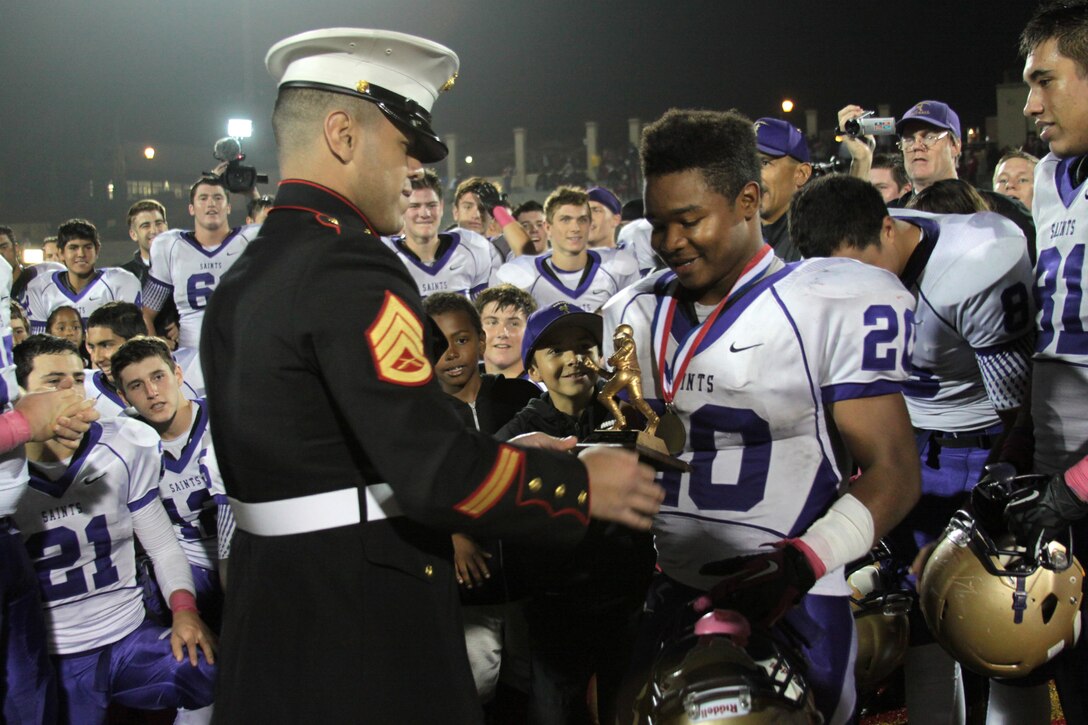 Staff Sgt. Jonathan Morales, a recruiter with Recruiting Sub Station National City, RS San Diego, presents Elijah Preston, a running back for St. Augustine High School's football team, the most valuable player award after their game against Cathedral Catholic High School during the Great American Rivalry Series at CCHS, San Diego, Oct. 25. The St. Augustine Saints won 19-7. 