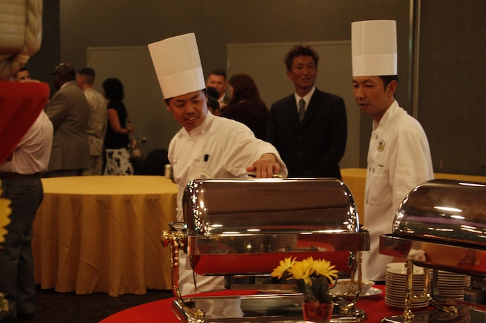 Mori Nobu, right, Club Iwakuni sous chef, walks with another chef as they check food preparation before serving it at a reception for Col. James C. Stewart, former station commanding officer, in the Club Iwakuni ballroom at Marine Corps Air Station Iwakuni, Japan, July 12, 2013. Nobu helps prepare the food once Troy Guyer, Club Iwakuni executive chef, finishes writing out the menu.