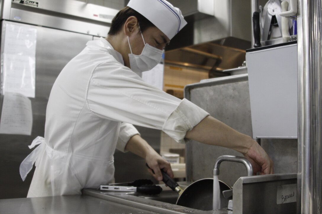 Yasunobu Asaeda, Club Iwakuni supervisor, washes a pan used to complete an order during a busy breakfast rush at Club Iwakuni at Marine Corps Air Station Iwakuni, Japan, July 20, 2013. When the number of people working is low, Asaeda steps in to take care of miscellaneous tasks, such as washing dishes. 