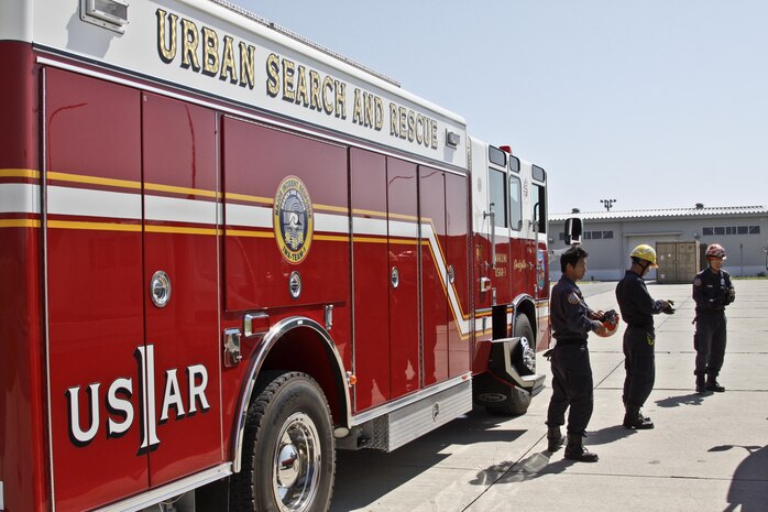 Firefighters from Marine Corps Air Station Iwakuni, Japan, prepare to suit up for their practical application exam during the Urban Search and Rescue Technical Search Training course Aug. 27, 2013.