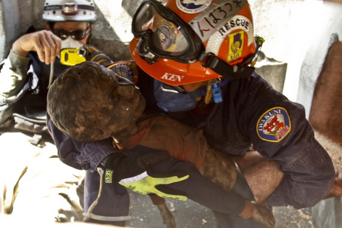 Ken Kobayashi, station fire department crew chief, extracts a training dummy from a simulated collapse for their practical application exam during the Urban Search and Rescue Technical Search Training course Aug. 28, 2013. According To Harry Muns, Chula Vista, Calif., battalion chief and course instructor, one of the primary goals of the training is to ensure firefighters are able to perform their tasks efficiently with the limited personnel they have.