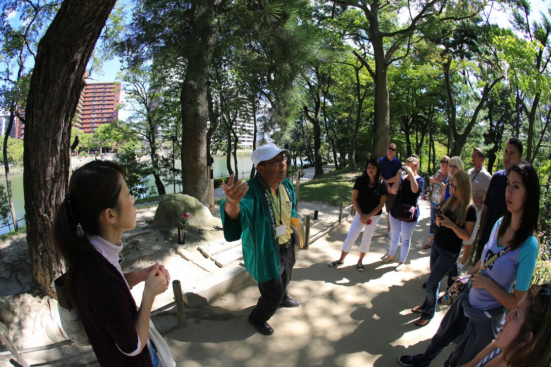 Fujio Tsuda, a tour guide at the Shukkeien Garden, stops to tell a group of Marine Corps Air Station Iwakuni, Japan, residents about the tale of a group of Japanese locals who survived the Hiroshima atomic bombing Sept. 27, 2013. The tale tells of a group of Hiroshima residents that survived the bombing and came to the pond in the middle of the gardens to drink after the explosion. Soon after, they all died lying face-down from radiation.