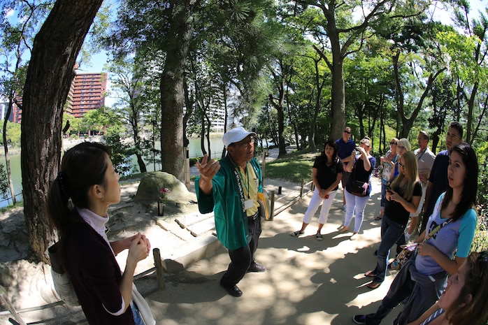Fujio Tsuda, a tour guide at the Shukkeien Garden, stops to tell a group of Marine Corps Air Station Iwakuni, Japan, residents about the tale of a group of Japanese locals who survived the Hiroshima atomic bombing Sept. 27, 2013. The tale tells of a group of Hiroshima residents that survived the bombing and came to the pond in the middle of the gardens to drink after the explosion. Soon after, they all died lying face-down from radiation.