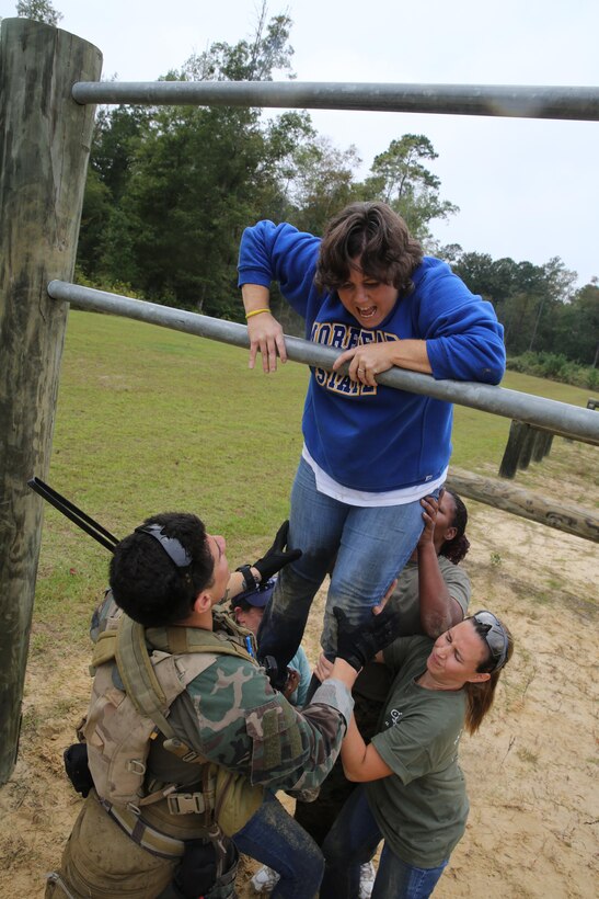 Participants of a Jane Wayne Day event run through an obstacle course on Camp Lejeune, N.C., Oct. 19, 2013.  The event was organized by Marine Special Operations Regiment, allowing wives of MARSOC personnel to experience firsthand how Critical Skills Operators train for missions.  This Jane Wayne Day event immersed participants in an interactive scenario comprising patrols, a run through an obstacle course, rides on zodiac boats, encounters with role-players and a simulated raid on a town.  MARSOC Marines supervised the entire event, and assisted the family members throughout the scenario.(U.S. Marine Corps Photo by Lance Cpl. Steven Fox/Released)