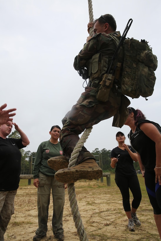 Participants of a Jane Wayne Day event run through an obstacle course on Camp Lejeune, N.C., Oct. 19, 2013.  The event was organized by Marine Special Operations Regiment, allowing wives of MARSOC personnel to experience firsthand how Critical Skills Operators train for missions.  This Jane Wayne Day event immersed participants in an interactive scenario comprising patrols, a run through an obstacle course, rides on zodiac boats, encounters with role-players and a simulated raid on a town.  MARSOC Marines supervised the entire event, and assisted the family members throughout the scenario. (U.S. Marine Corps Photo by Lance Cpl. Steven Fox/Released)