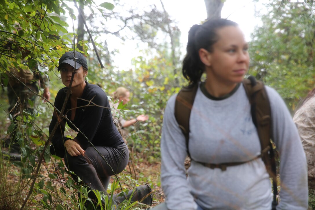 Participants of a Jane Wayne Day event patrol through vegetation on Camp Lejeune, N.C., Oct. 19, 2013.  The event was organized by Marine Special Operations Regiment, allowing wives of MARSOC personnel to experience firsthand how Critical Skills Operators train for missions.  This Jane Wayne Day event immersed participants in an interactive scenario comprising patrols, a run through an obstacle course, rides on zodiac boats, encounters with role-players and a simulated raid on a town.  MARSOC Marines supervised the entire event, and assisted the family members throughout the scenario. (U.S. Marine Corps Photo by Lance Cpl. Steven Fox/Released)
