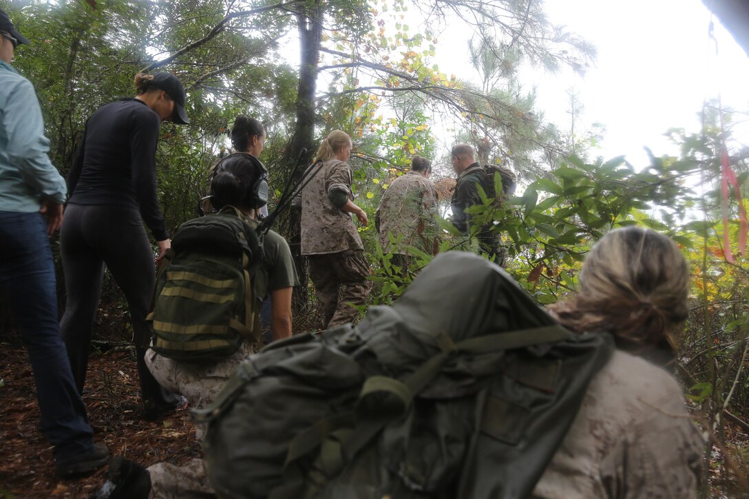 Participants of a Jane Wayne Day event patrol through vegetation on Camp Lejeune, N.C., Oct. 19, 2013.  The event was organized by Marine Special Operations Regiment, allowing wives of MARSOC personnel to experience firsthand how Critical Skills Operators train for missions.  This Jane Wayne Day event immersed participants in an interactive scenario comprising patrols, a run through an obstacle course, rides on zodiac boats, encounters with role-players and a simulated raid on a town.  MARSOC Marines supervised the entire event, and assisted the family members throughout the scenario. (U.S. Marine Corps Photo by Lance Cpl. Steven Fox/Released)