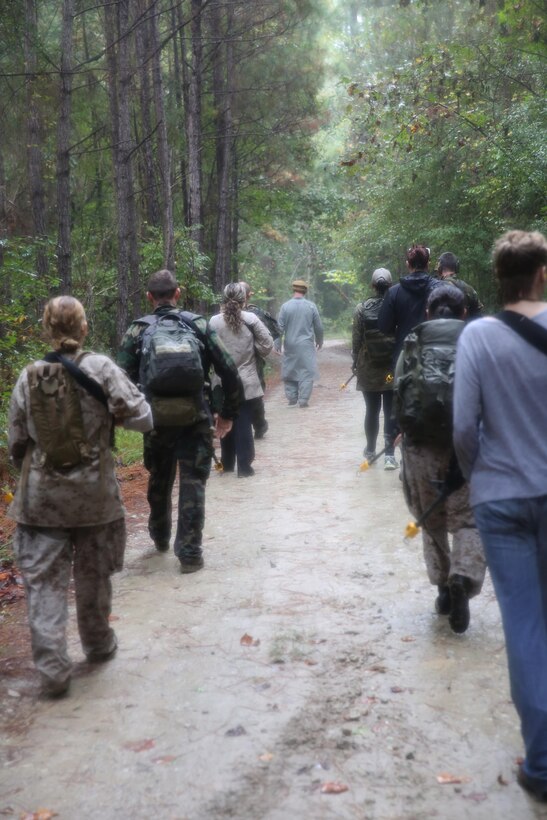 Participants of a Jane Wayne Day event patrol in a tactical formation as they advance to the location of a simulated raid on a town at Camp Lejeune, N.C., Oct. 19, 2013.  The event was organized by Marine Special Operations Regiment, allowing wives of MARSOC personnel to experience firsthand how Critical Skills Operators train for missions.  This Jane Wayne Day event immersed participants in an interactive scenario comprising patrols, a run through an obstacle course, rides on zodiac boats, encounters with role-players and a simulated raid on a town.  MARSOC Marines supervised the entire event, and assisted the family members throughout the scenario. (U.S. Marine Corps Photo by Lance Cpl. Steven Fox/Released)