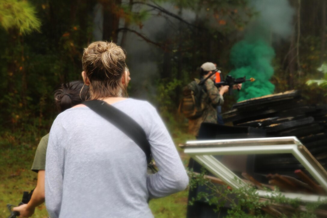 Participants of a Jane Wayne Day event raid a town during the last portion of a simulated special operations mission on Camp Lejeune, N.C., Oct. 19, 2013.  The event was organized by Marine Special Operations Regiment, allowing wives of MARSOC personnel to experience firsthand how Critical Skills Operators train for missions.  This Jane Wayne Day event immersed participants in an interactive scenario comprising patrols, a run through an obstacle course, rides on zodiac boats, encounters with role-players and a simulated raid on a town.  MARSOC Marines supervised the entire event, and assisted the family members throughout the scenario. (U.S. Marine Corps Photo by Lance Cpl. Steven Fox/Released)
