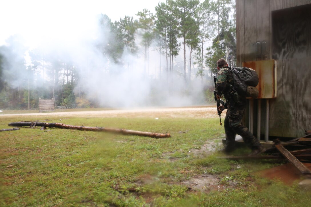 Participants of a Jane Wayne Day event raid a town during the last portion of a simulated special operations mission on Camp Lejeune, N.C., Oct. 19, 2013.  The event was organized by Marine Special Operations Regiment, allowing wives of MARSOC personnel to experience firsthand how Critical Skills Operators train for missions.  This Jane Wayne Day event immersed participants in an interactive scenario comprising patrols, a run through an obstacle course, rides on zodiac boats, encounters with role-players and a simulated raid on a town.  MARSOC Marines supervised the entire event, and assisted the family members throughout the scenario. (U.S. Marine Corps Photo by Lance Cpl. Steven Fox/Released)