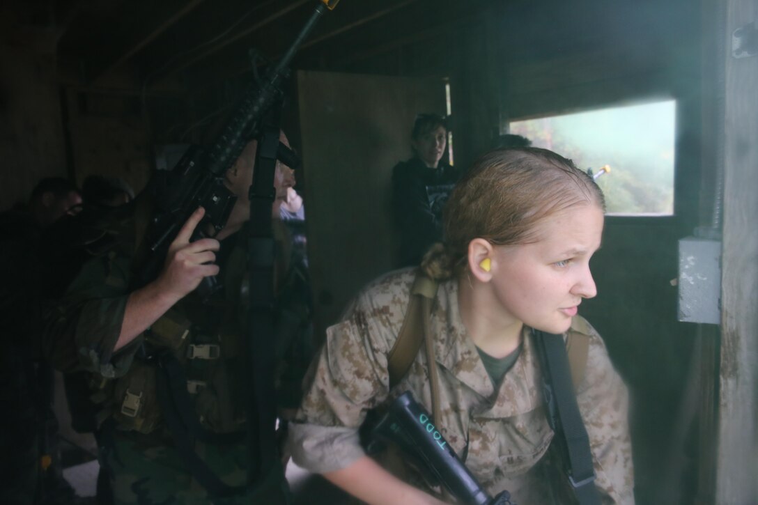 Participants of a Jane Wayne Day event raid a town during the last portion of a simulated special operations mission on Camp Lejeune, N.C., Oct. 19, 2013.  The event was organized by Marine Special Operations Regiment, allowing wives of MARSOC personnel to experience firsthand how Critical Skills Operators train for missions.  This Jane Wayne Day event immersed participants in an interactive scenario comprising patrols, a run through an obstacle course, rides on zodiac boats, encounters with role-players and a simulated raid on a town.  MARSOC Marines supervised the entire event, and assisted the family members throughout the scenario. (U.S. Marine Corps Photo by Lance Cpl. Steven Fox/Released)