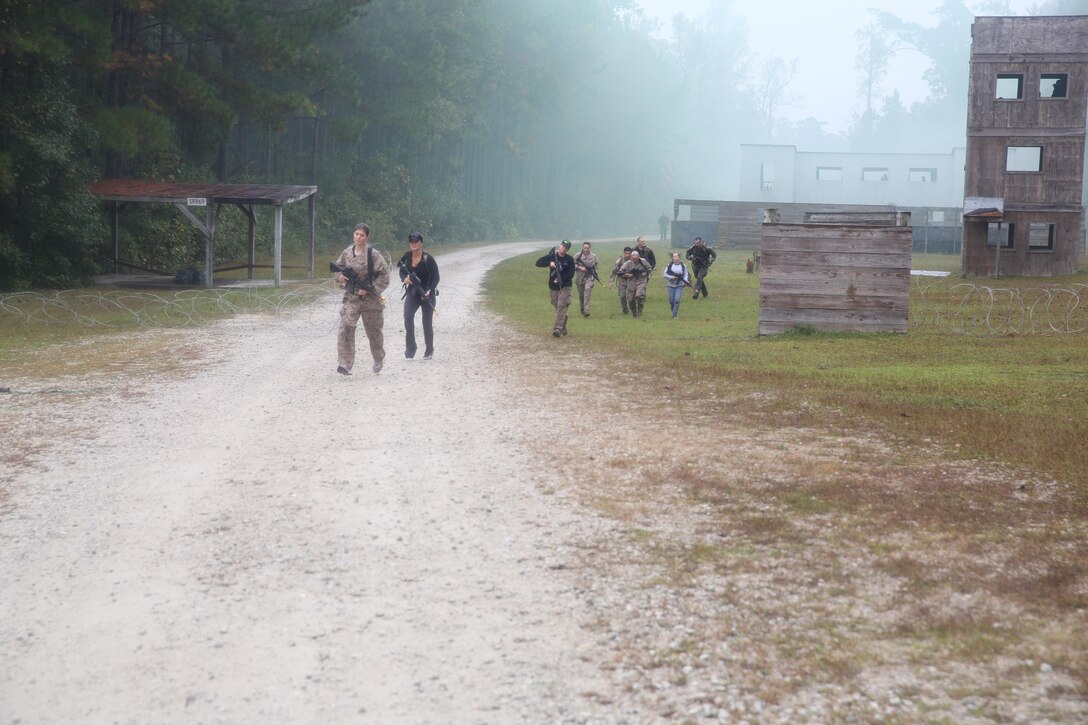 Participants of a Jane Wayne Day event raid a town during the last portion of a simulated special operations mission on Camp Lejeune, N.C., Oct. 19, 2013.  The event was organized by Marine Special Operations Regiment, allowing wives of MARSOC personnel to experience firsthand how Critical Skills Operators train for missions.  This Jane Wayne Day event immersed participants in an interactive scenario comprising patrols, a run through an obstacle course, rides on zodiac boats, encounters with role-players and a simulated raid on a town.  MARSOC Marines supervised the entire event, and assisted the family members throughout the scenario. (U.S. Marine Corps Photo by Lance Cpl. Steven Fox/Released)