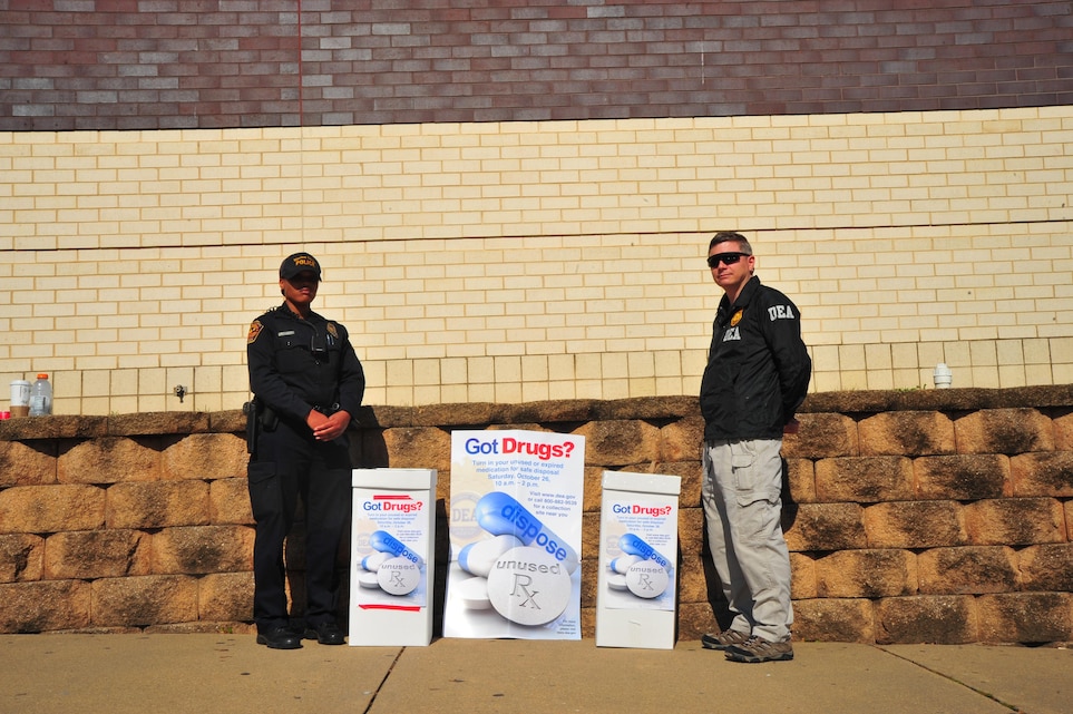 Brandi Salvant, officer, Provost Marshal Office, and Drug Enforcement Administration Agent Michael A. Beyer, stand at their drug drop-off point at the Marine Corps Exchange as part of the “National Drug Take Back Initiative”  hosted by Security Battalion on Oct. 23, 2013. This is the fourth year in a row Security Battalion has hosted the event. (Marine Corps Photo by Lance Cpl. Cuong Le/Released)