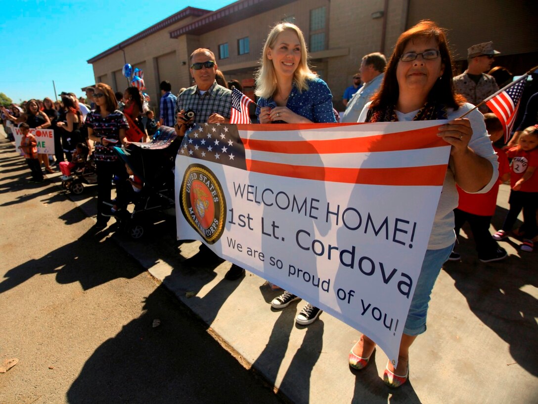 In anticipation of her husband's return, Marissa Cordova, wife of 1st Lt. Charlie Cordova, holds a sign with her husband's parents during a homecoming celebration aboard Camp Pendleton, Calif., Oct. 18. The newlyweds only spent six days together before Cordova's 10-month deployment to Afghanistan.