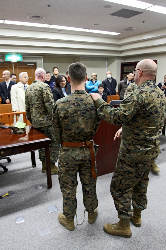 Master Sgt. Wade Campbell, (Right) pre-trial facilities officer-in-charge, and Lance Cpl.
Frank Pikula, (Left) legal services clerk, demonstrate restraint equipment used to subdue
hostile defendants awaiting trial in the pre-trial facility of the Station Judge Advocates
courtroom here, Feb. 7, 2013, during an outreach program offered to Hatsukaichi police
inspectors.