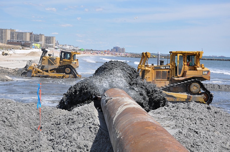 A sand and water slurry mixture pumps onto Rockaway Beach on August 15, 2013 as part of beach renourishment efforts there. The angle shows the severely eroded areas where sand will be placed next as well as some of the densely populated areas where the sand being placed will help to reduce risk from future storms. Post-Sandy sand placement activities are underway at Rockaway Beach in Queens, NY as part of a project placing roughly 3.5 million cubic yards onto the beach to help reduce risks from future storms
