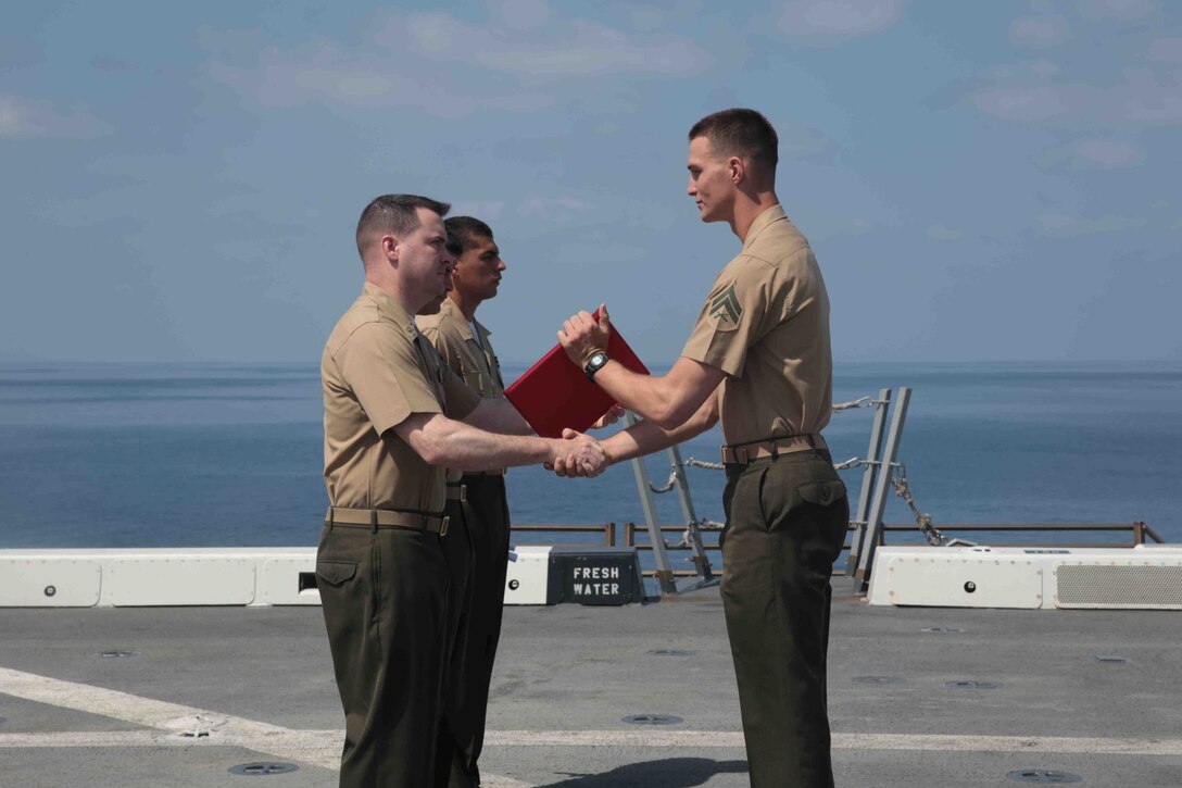 U.S. Marine Corps Cpl. Cody Beck, right, a rifleman with Battalion Landing Team 1/4, 13th Marine Expeditionary Unit receives the "Gung Ho" award during the graduation ceremony for Corporals' course aboard the flight deck of the USS New Orleans (LPD 18) Oct. 19, 2013. The 13th MEU is deployed with the Boxer Amphibious Ready Group as a theater reserve and crisis response force throughout the U.S. 5th Fleet area of responsibility. (U.S. Marine Corps photo by Cpl. David Gonzalez, 13th Marine Expeditionary Unit Combat Camera/Released)