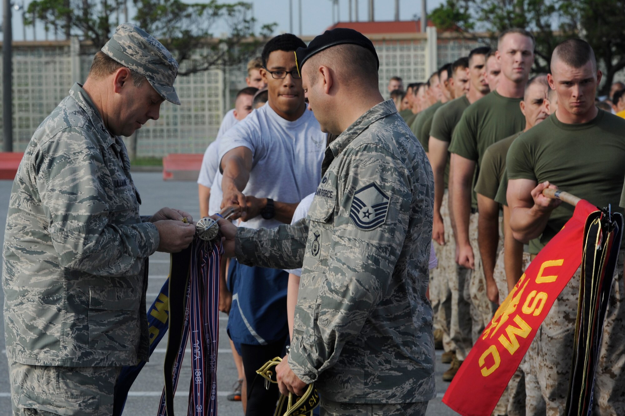 U.S. Air Force Col. Jeffrey Ullman, 18th Mission Support Group commander, and Master Sgt. Neil Puttbrese, 18th Security Forces superintendant of standardization and evaluation, attach Kadena Special Olympics ribbons onto the guidons of the joint military formation at Kadena Air Base, Japan, Oct. 26, 2013. More than 70 military members ran together for the KSO torch run. (U.S. Air Force photo by Senior Airman Marcus Morris) 