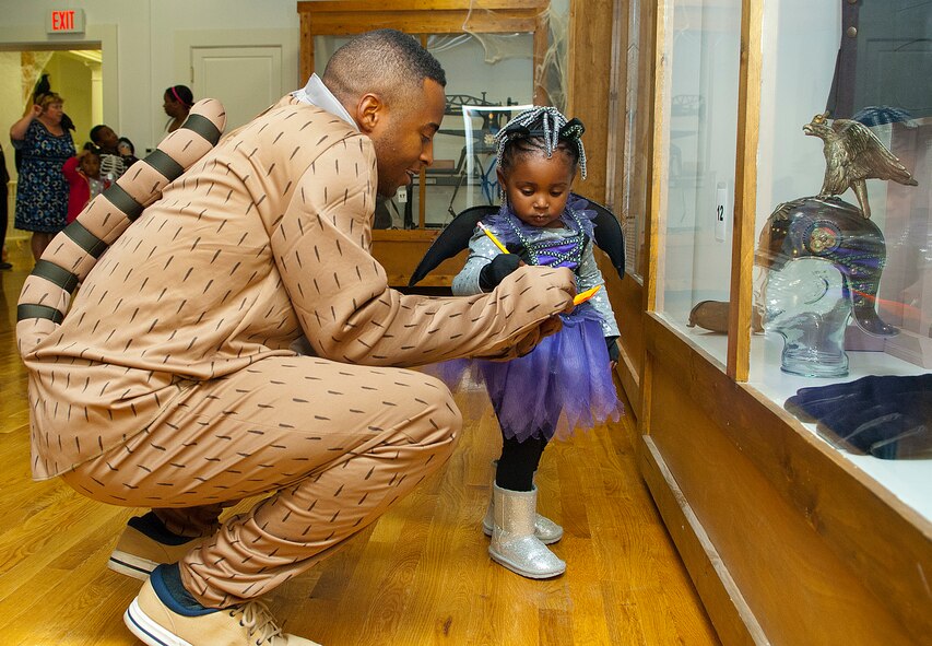 131025-F-CP692-001
Senior Airman Darnell Herron, 391th Missile Squadron, helps his daughter, Kennedy, 2, look for ghosts in the display cases at the museum Oct. 25. Kennedy won first place in the costume contest for children, ages 0-3. This is the first year the museum staff and volunteers organized this event to include a pumpkin carving contest, scavenger hunt, costume contest, trivia, and old "scary" movies and popcorn.  First place costume contest winners: Kennedy Herron, 2 (ages 0-3); James Hayes, 10 (ages 4-12); Ashley Calkins, 13 (ages 13-18); and Pam Gunn, 90th Medical Operations Squadron (Adult). (Photo by 1st Lt. Eydie Sakura)