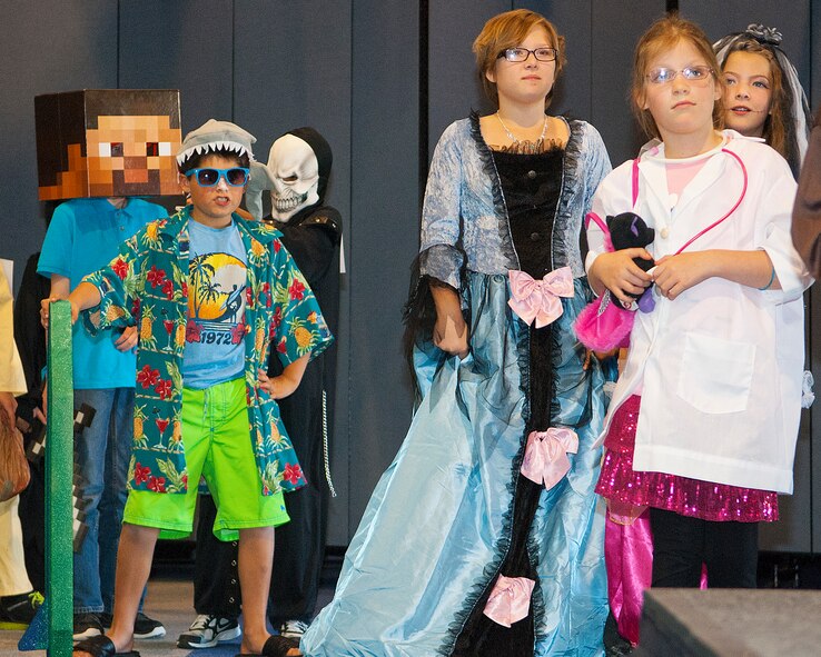 Children line-up to cross the stage during a costume contest at the "Trick-or-Treat-off-the-Street" event Oct. 26, 2013 in the Fall Hall Community Center. Of the nearly 600 attendees, approximately 200 children and adults participated in the costume contest based on age categories. There was also a free spaghetti buffet, haunted house, pumpkin carving contest, Trunk or Treat, carnival games and bouncy castles. The costume contest winners were: ages 0-3, Landon Knight as “Chucky;” ages 4-7, Karleyann Stephens as “‘80s girl;” ages 8-12, Esai Comes as “Boy with E.T.;” ages 13-18, Aaron Gootee as “Mummy;” and family group, the Fehlberg family as “Fairies.” (Photo by 1st Lt. Eydie Sakura)