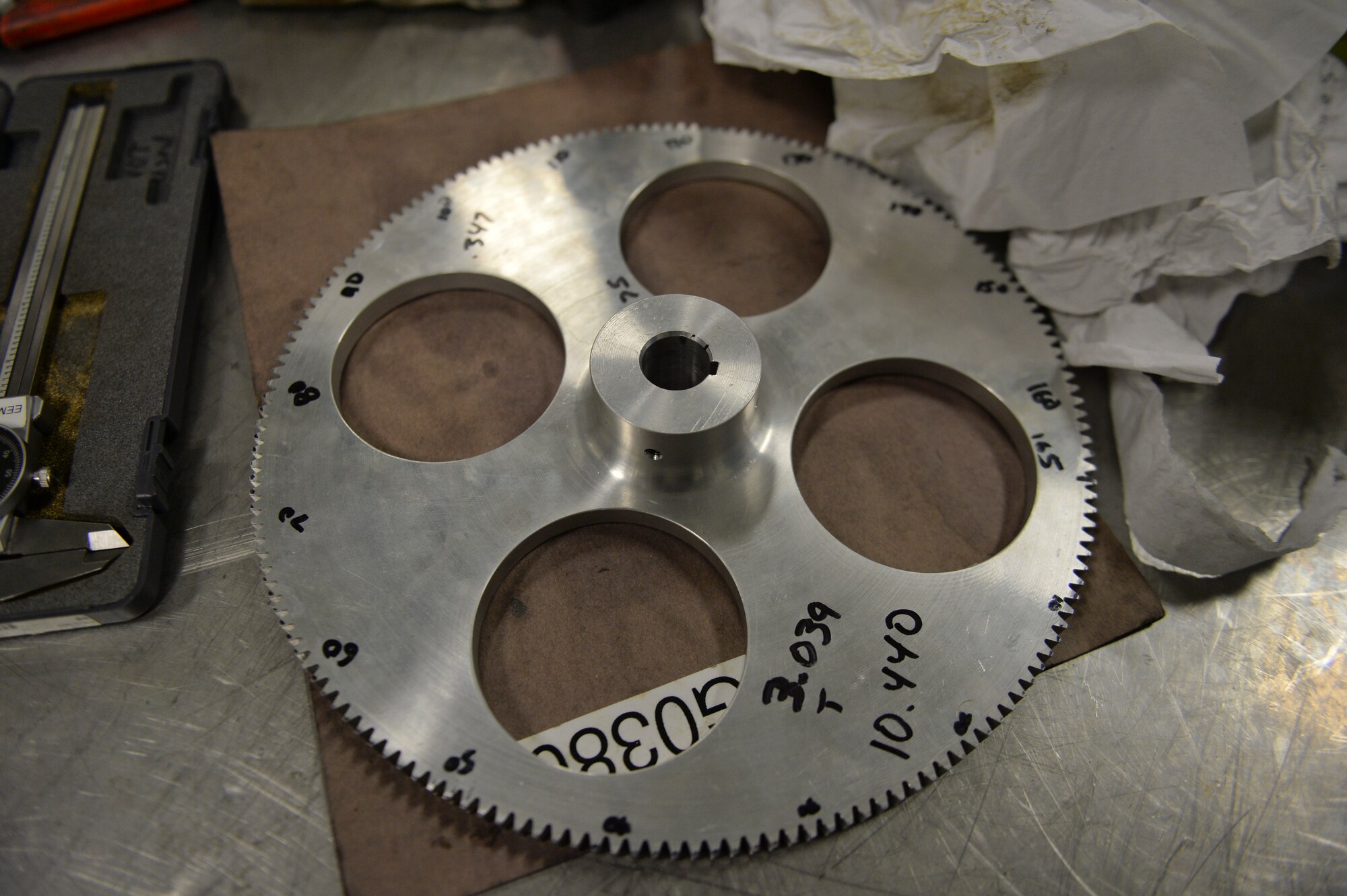 A newly-created machine gear sits on a work table at the metals technology shop at Hurlburt Field, Fla. Oct. 24, 2013. The gear created in the shop on a vertical machining center is used by technicians to build custom aircraft parts.(U.S. Air Force Photo/ Staff Sgt. John Bainter)