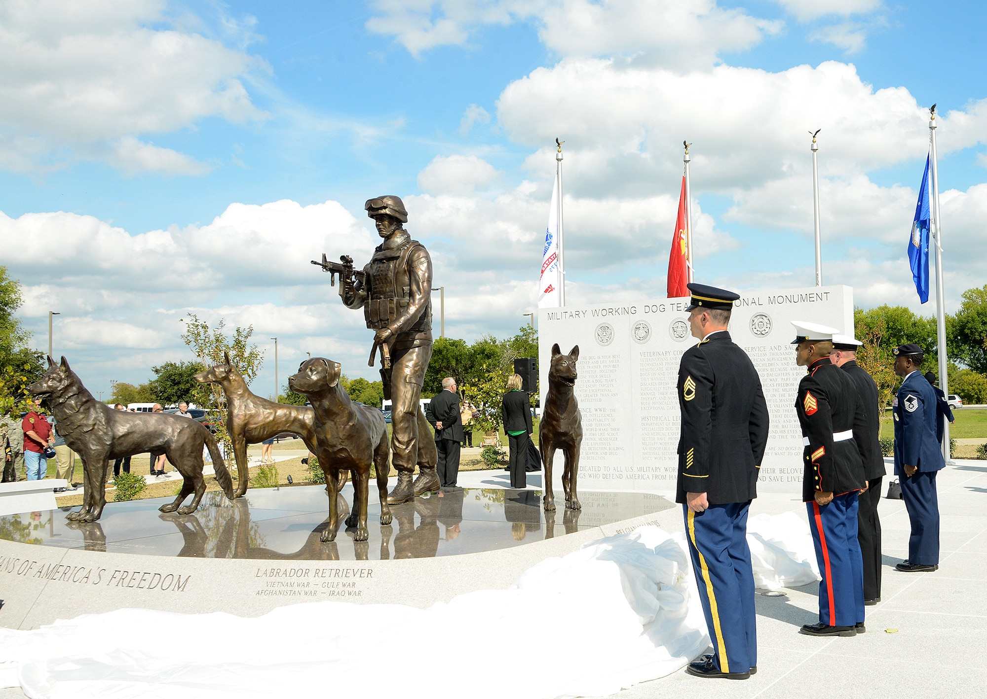 Military members stand at attention as the service flags are raised at the U.S. Military Working Dog Teams National Monument Oct. 28, at Joint Base San Antonio-Lackland. JBSA-Lackland is the home to the Department of Defense Military Working Dog Program and is where the U.S. Armed Forces has been training its military working dog teams since 1958. It is the world's largest training center for military dogs and handlers and is also home to the largest veterinary hospital for military working dogs. (U.S. Air Force photo by Benjamin Faske) (released)