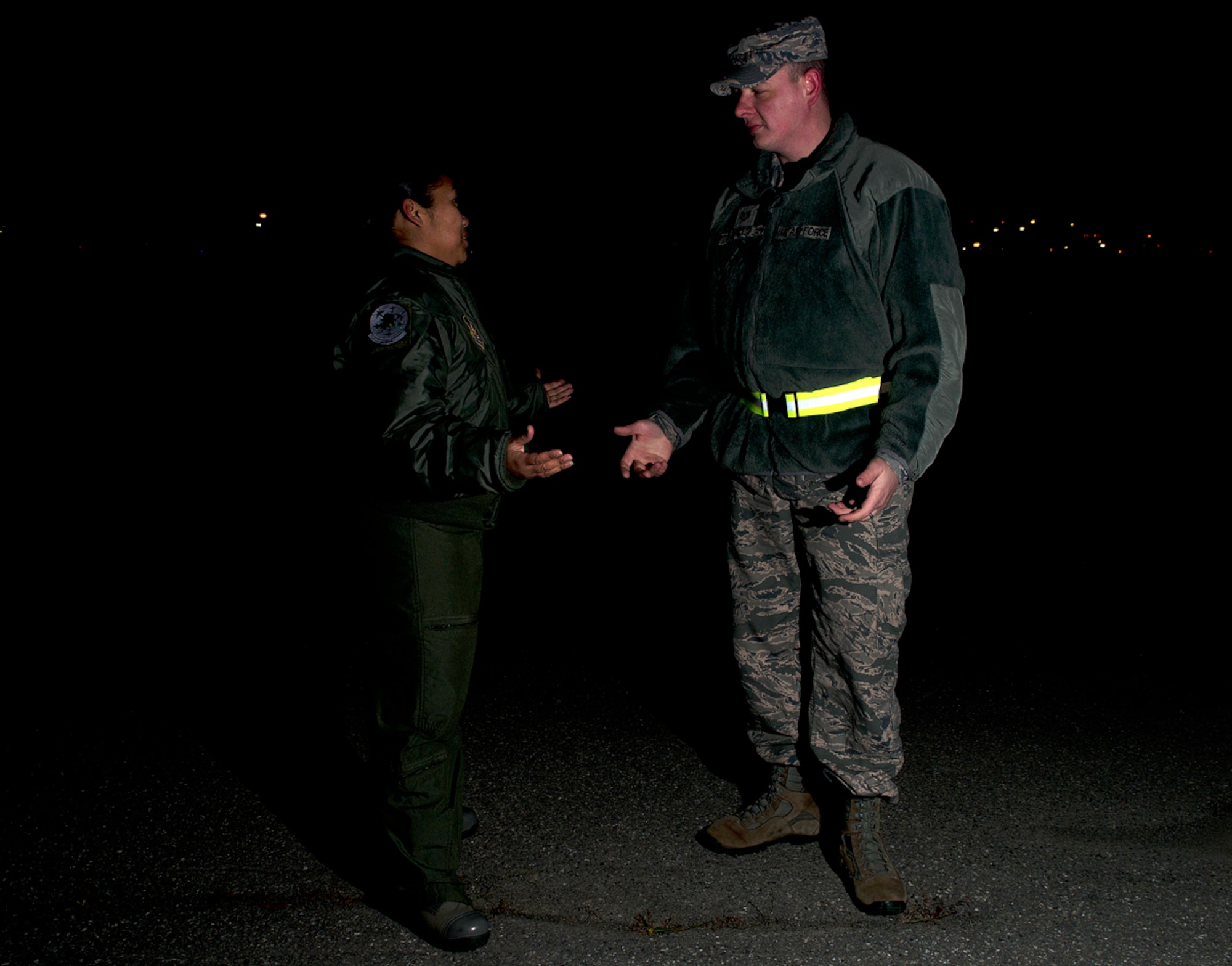 Air Force Staff Sgt. Sheila deVera and Tech. Sgt. Raymond Mills, 673d Air Base Wing Public Affairs photojournalists, demonstrate why wearing a reflective belt to be seen is important. All uniformed military members on Joint Base Elmendorf-Richardson are required to wear reflective belts or a reflective material while outside on base during hours of darkness and inclement weather. Safety officials urge everyone, whether in uniform or not, to abide by this policy. The material used to create a reflective belt bounces light back at the source, making it easier for drivers to see pedestrians and cyclists. A reflective belt is not required while wearing Air Force physical training uniforms, since it is made with reflective material, but Army PT uniforms require reflective belts. JBER instruction 91-202 explains, in detail, when and where reflective belts must be worn, but a good rule of thumb is if it is less than full daylight conditions, wear the belt. (U.S. Air Force photo/Staff Sgt. Zachary Wolf)