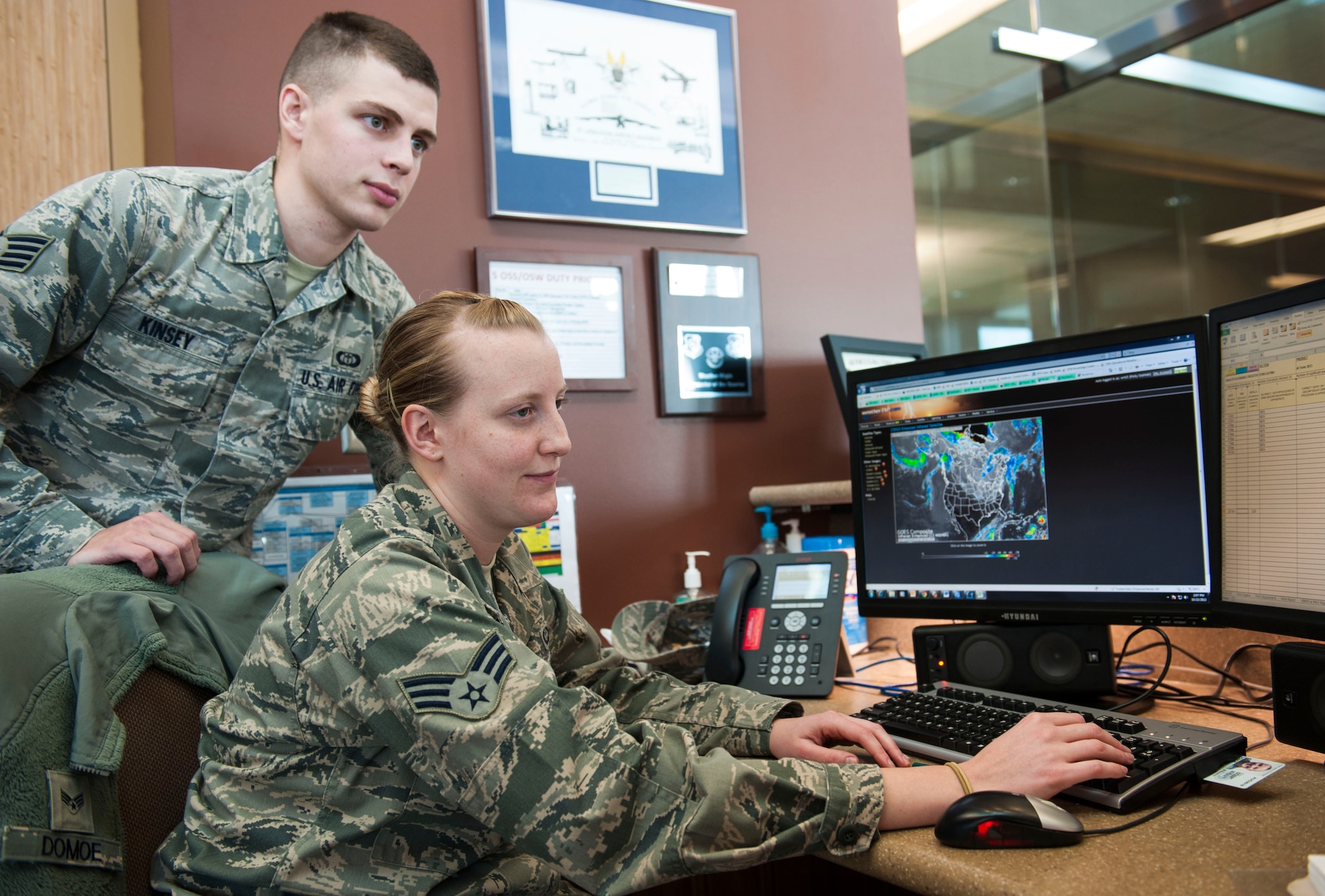 Staff Sgt. Zak A. Kinsey, 5th Operations Support Squadron noncommissioned officer in charge of mission weather, checks the work of Senior Airman Courtney Domoe, 5th OSS weather forecaster, Oct. 23. The Weather Flight is currently preparing for the harsh North Dakota winter ahead. Their forecast accuracy is crucial for mission readiness. (U.S. Air Force photo/Airman 1st Class Apryl Hall)