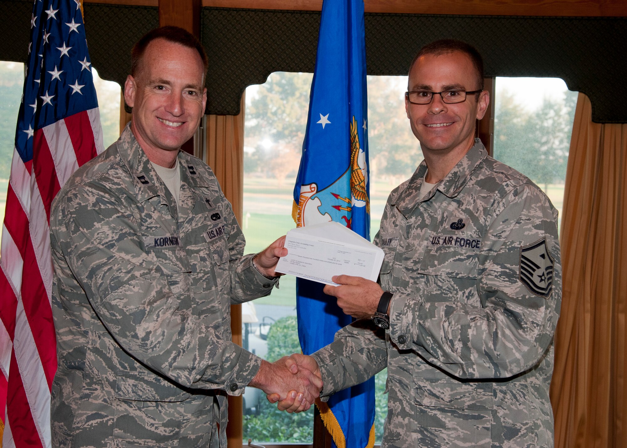 U.S. Air Force Capt. Joel Kornegay, 633rd Air Base Wing chaplain, presents a donation check to Master Sgt. Ryan McCauley, 633rd Civil Engineer Squadron first sergeant, during the Langley First Sergeants Council meeting at Langley Air Force Base, Va., Oct. 25, 2013. The wing’s Protestant and Catholic ministries donated more than $7,000 to the LFSC’s Operation Warmheart program, an annual campaign that supports Langley Airmen in need through a variety of charitable means, including holiday food baskets, loans and clothing donations. (U.S. Air Force photo by Senior Airman Jason J. Brown/Released)