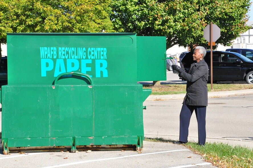 Base employee Estella Holmes deposits newspapers into a recycling center collection point for paper. (U.S. Air Force photo by Michele Eaton)