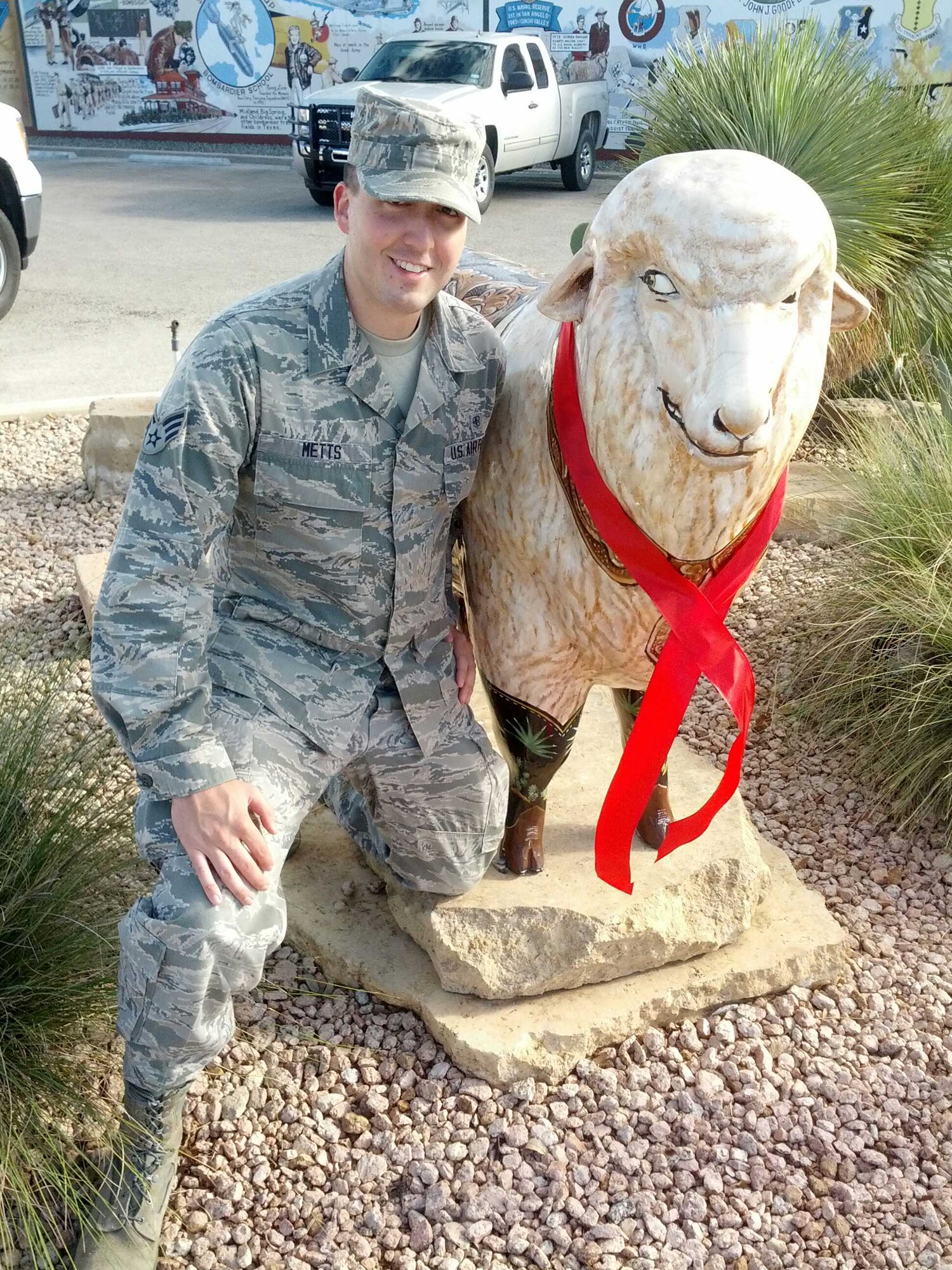 SAN ANGELO, Texas -- Senior Airman Charles Metts, 17th Medical Operations Squadron Alcohol and Drug Abuse Prevention and Treatment technician, stands with the Custom Made B“ewe”ts sheep on the corner of Oaks Street and Concho Avenue Oct. 24. Metts helped place red ribbons sheeps around the downtown San Angelo area to raise awareness during Red Ribbon Week. (Courtesy photo)