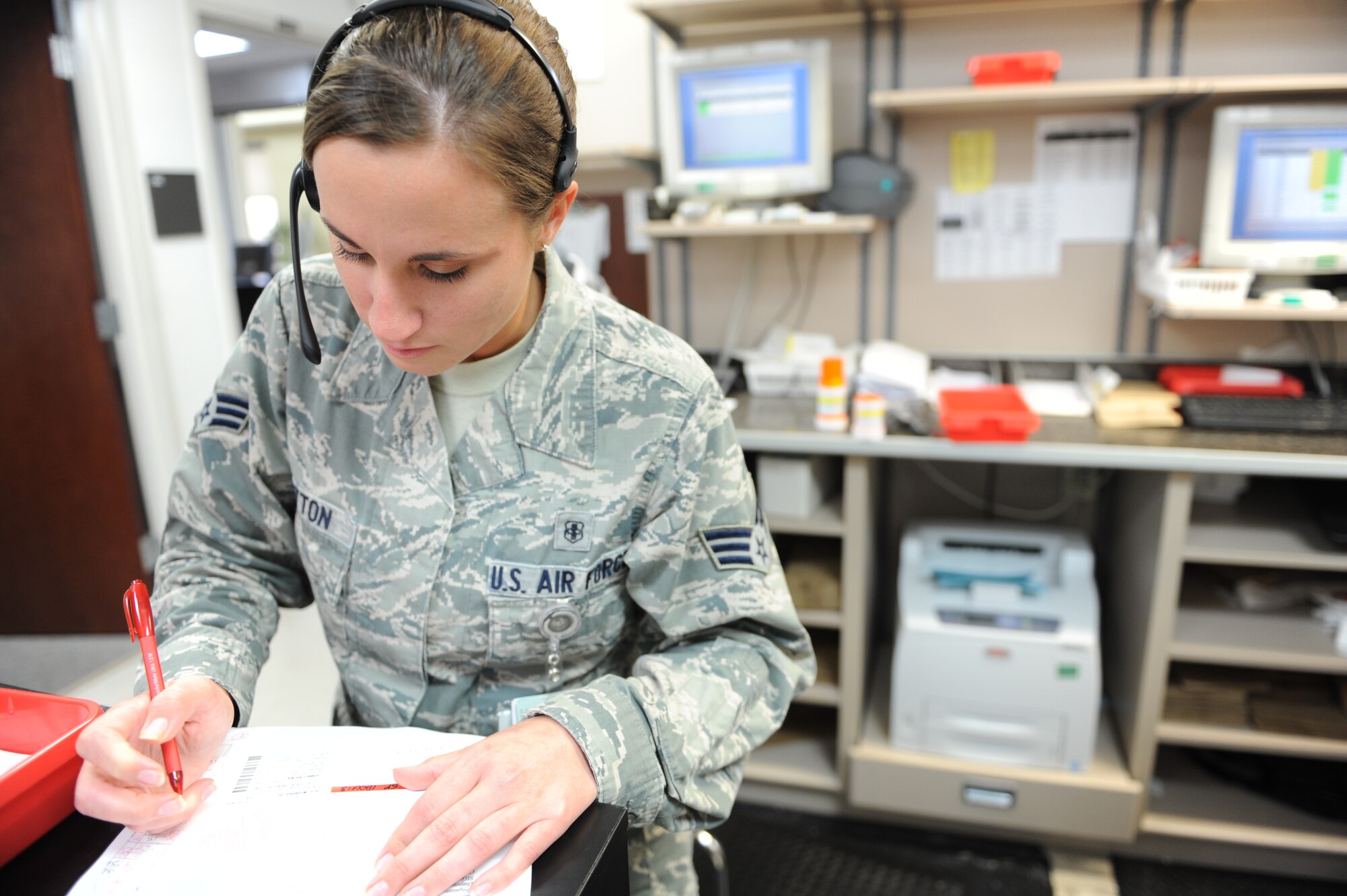 U.S. Air Force Senior Airman Sarah Patton, 7th Medical Support Squadron pharmacy technician, takes a customer’s question, while preparing paperwork for the patient’s medication at the Dyess pharmacy, Oct. 18, 2013, at Dyess Air Force Base, Texas.  Pharmacy technicians record paperwork by hand or electronically. (U.S. Air Force photo by Airman 1st Class Kedesha Pennant)